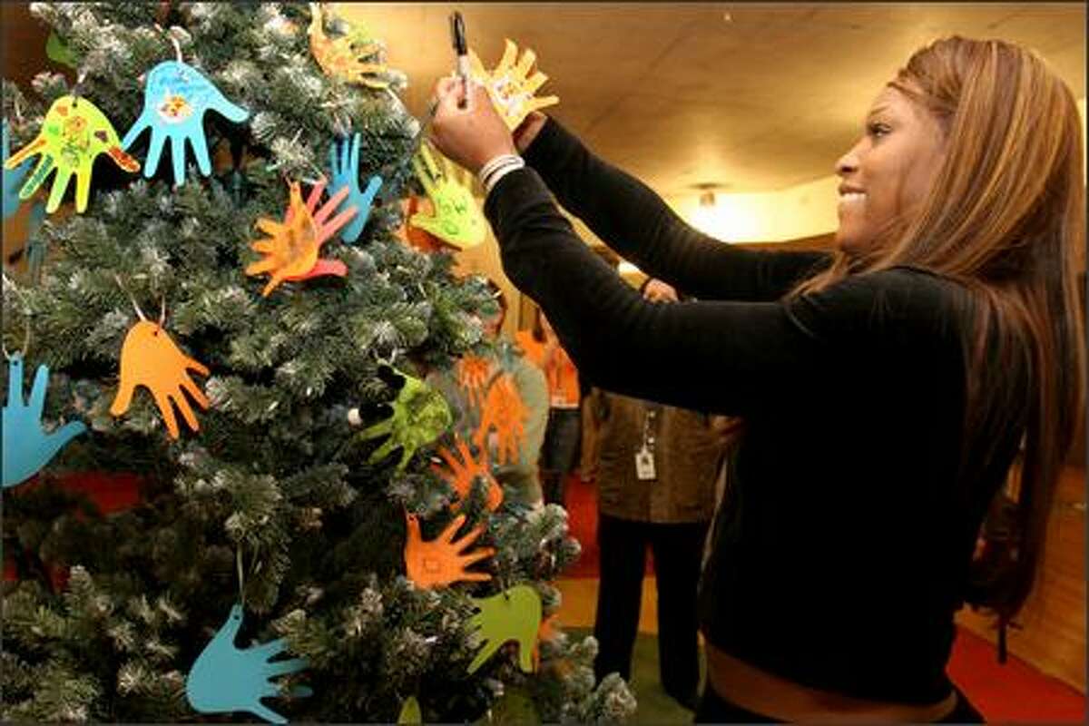 Serena Williams hangs a paper hand that she decorated on the Christmas tree at Ronald McDonald House in Seattle. The Williams sisters are visting Seattle as part of a three-city tour. Part of the proceeds from the tour benefit Ronald McDonald House Charities. The Seattle Ronald McDonald house can provide up to 80 families whose children are being treated at Children's Hospital.