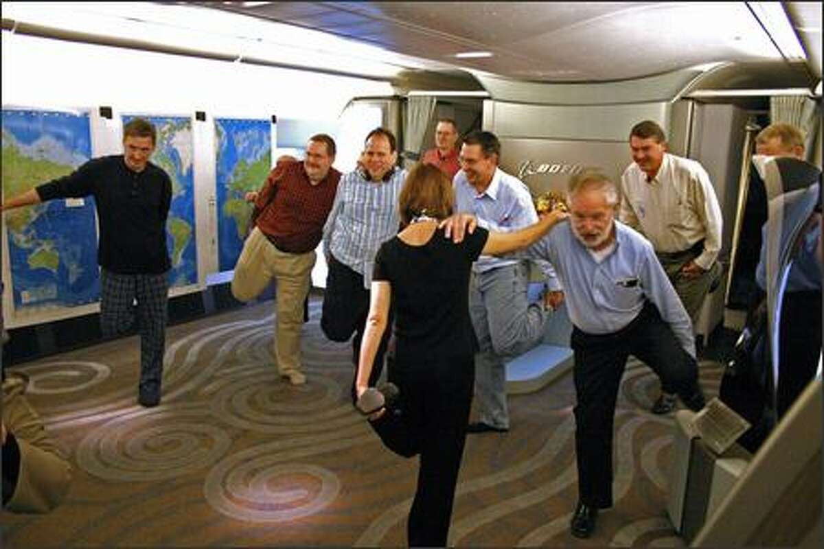 Flight attendant Maureen Walker leads some passengers in stretching exercises during the long flight. Holdng on to her is Don Philips, aerospace writer for the International Herald Tribune. The front cabin of the jet was empty of seats on this trip, leaving a large area for passengers to gather, talk and eat.