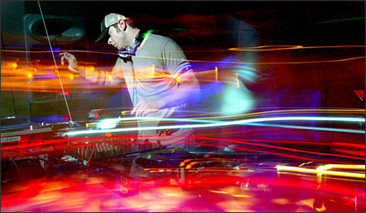 A swirl of sound -- represented by special camera effects -- wraps DJ Joshua James during the Spin-Off contest at Seattle's Element club. James, a finalist, lets the crowd's energy inspire his playlist. Haller: For those of you who have never watched a DJ, you should know that they don’t just sit there and play CDs. They are constantly moving back and forth between two or more turntables, a couple CD players, working a sound board, running a light show and trying to keep up some form of communication with the dancers in front of him. I wanted to convey this frenzy with a slow shutter speed, panning and selective lighting on Joshua James at Element.