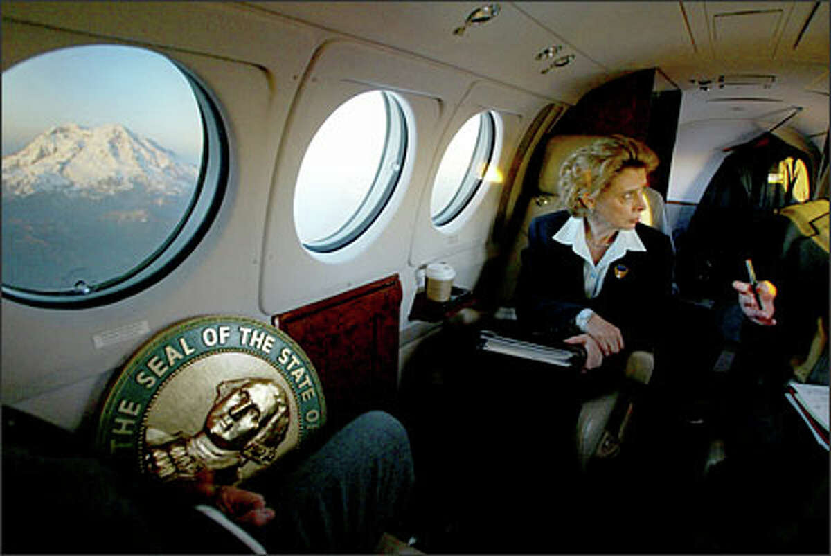 With Mount Rainier aglow in sunlight, Gov. Christine Gregoire focuses on a policy discussion during a return flight from Yakima to Olympia in March. She took a few brief moments to enjoy the view of the mountain, but soon after went back to work with Keith Phillips, her environmental policy adviser. Schenker: It was inconceivable to me that this photograph could have even been made. All the stars had to align: plane position, time of day, the window on the plane having a polarizing filter on it, and the seal of Washington being placed where it was.