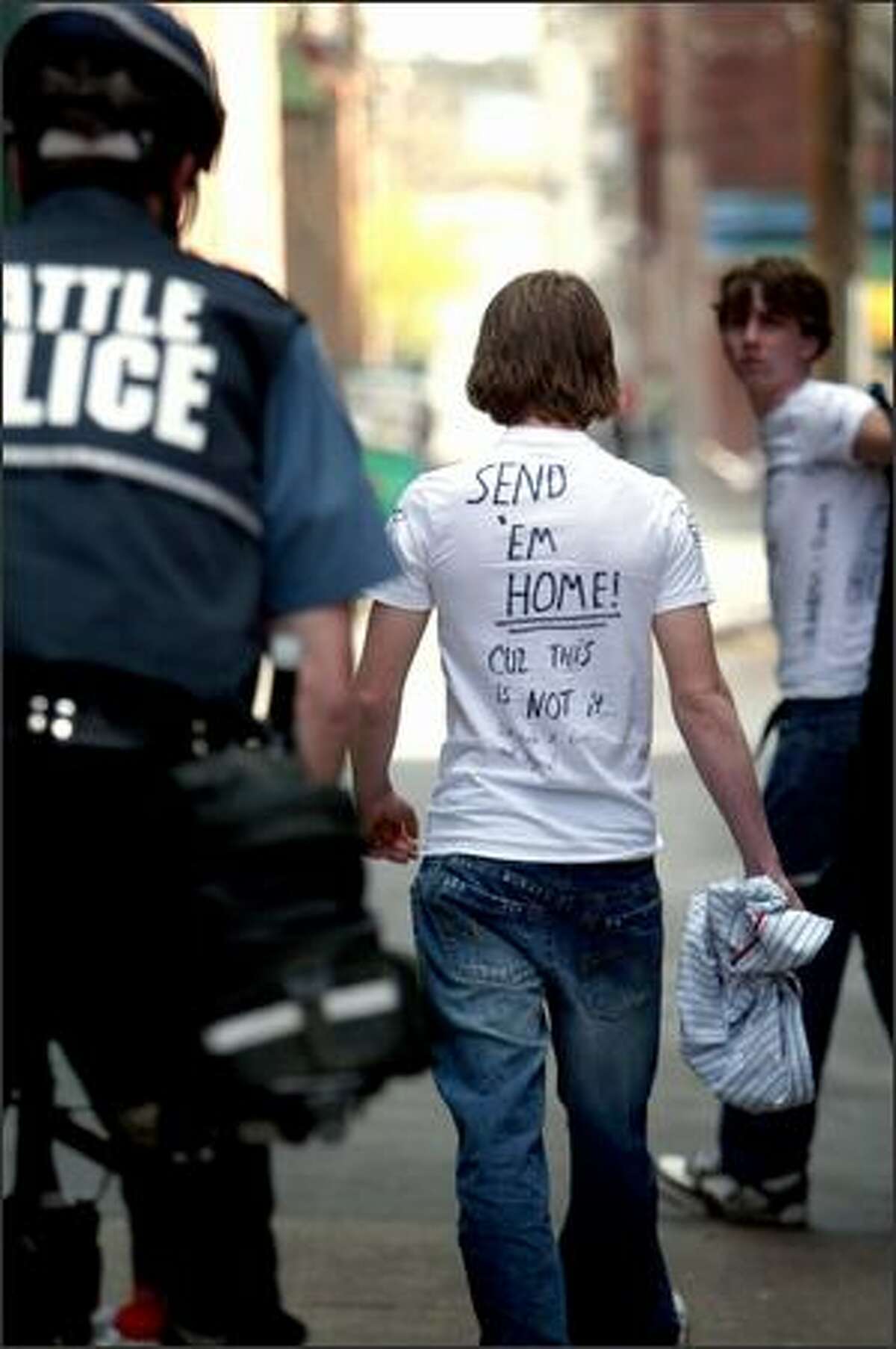 A self described white supremacist is escorted away after attempting to intercept the protest. The back of his T-shirt reads "SEND 'EM HOME! Cuz this is NOT it ... We stole it fair and square!"