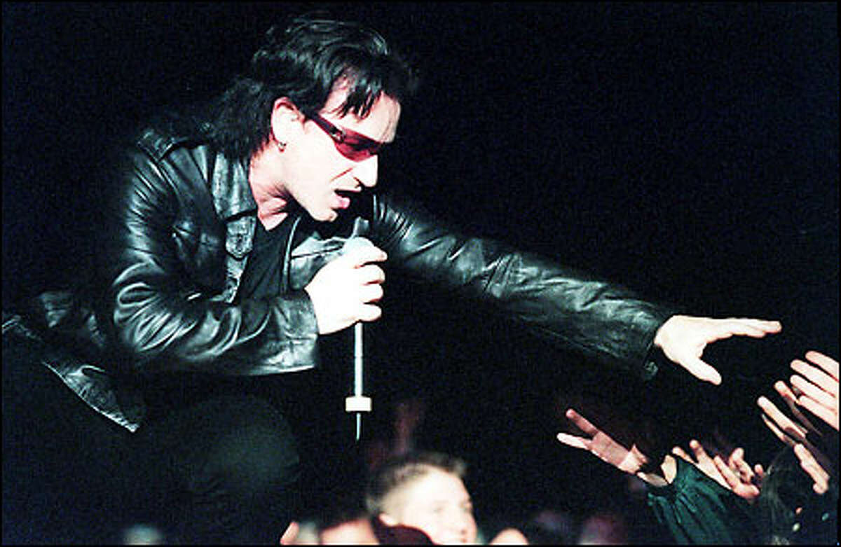 U2's lead singer Bono reaches out to the crowd pressing toward him on the catwalk stage during the "Elevation" tour's stop at the Tacoma Dome.