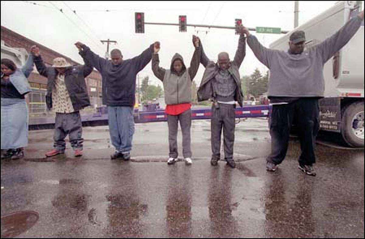 Holding hands, protesters form a circle at the intersection of 23rd Avenue East and East Union Street, during a demonstration yesterday sparked by the shooting death of Aaron Roberts. Protesters stopped traffic for several hours.