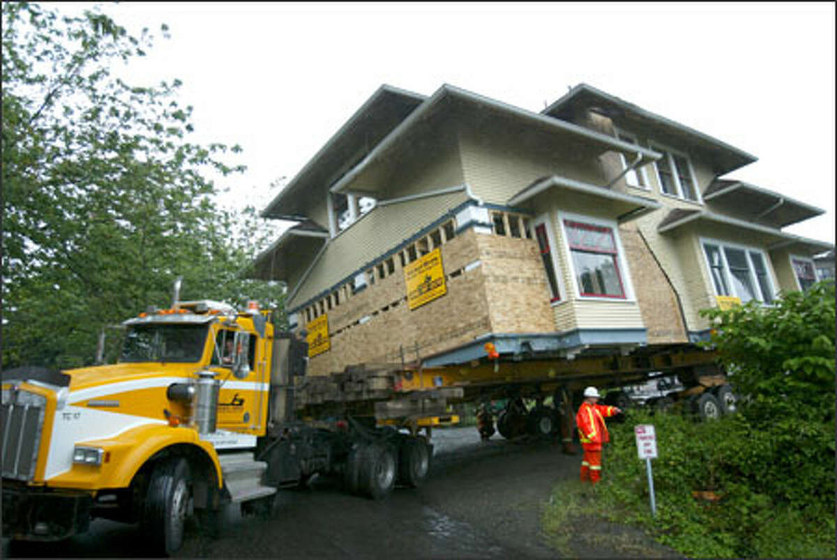 The last residential house on Seattle's Eastlake Avenue East negotiates a tricky turn Sunday on its way to a barge bound for the San Juan Islands, where new owners plan to preserve the 1908 house.