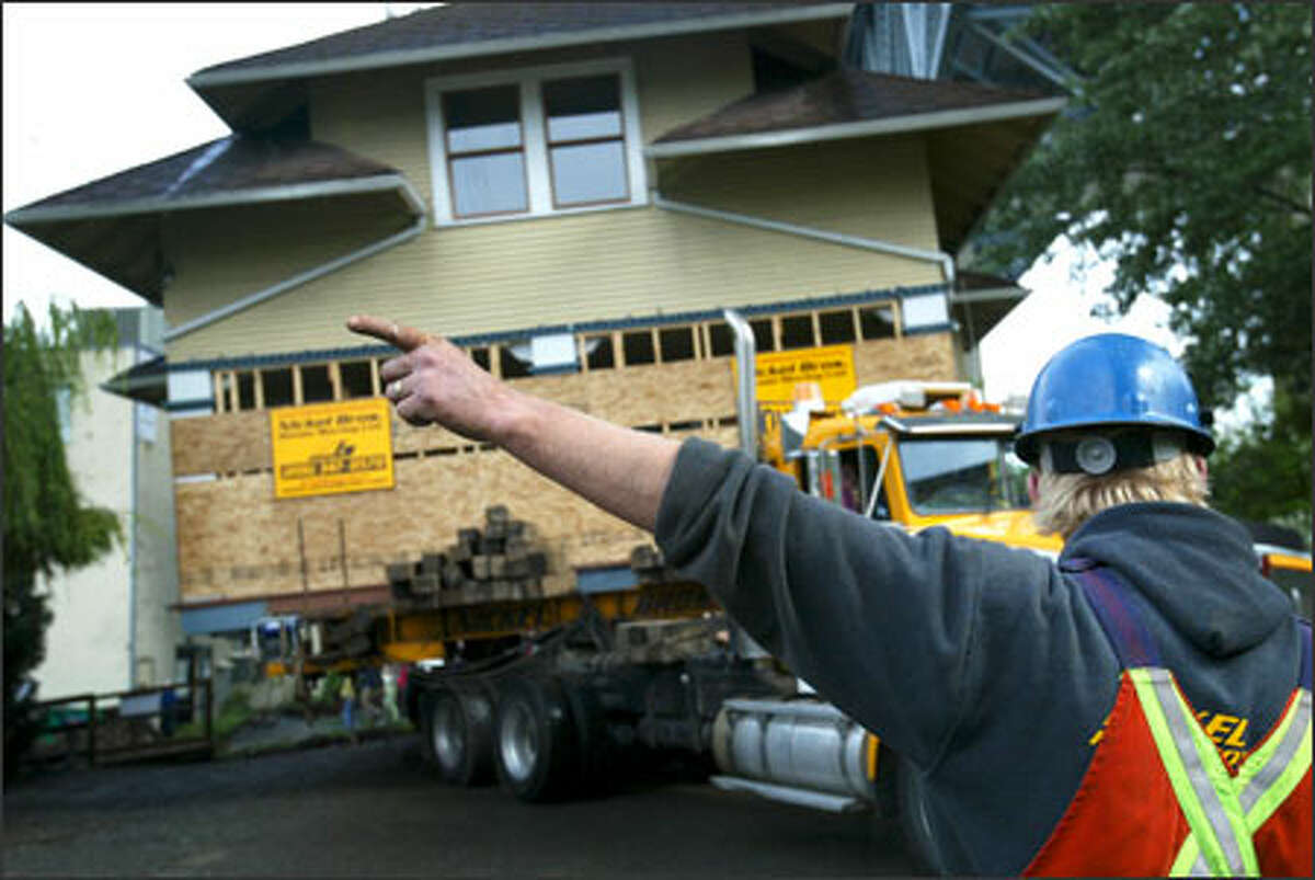 Jeremy Nickel directs a driver as the home begins its journey to a barge waiting on the water.