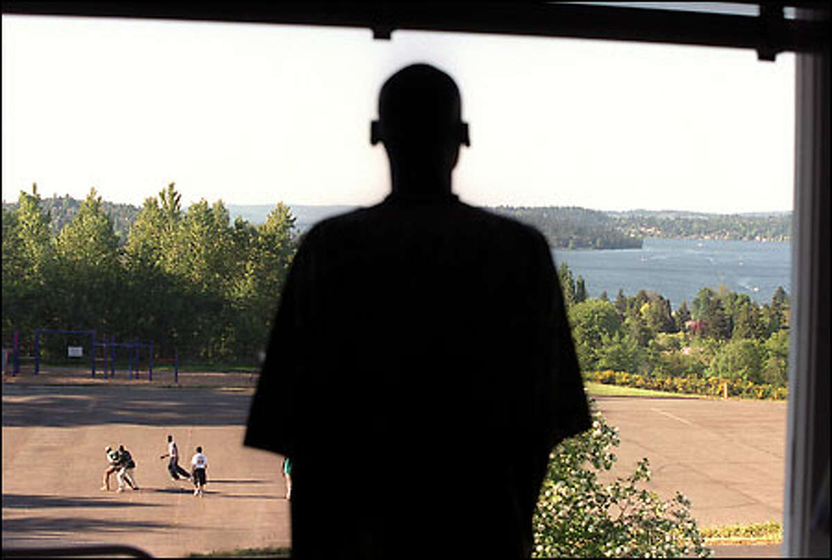 After arriving in the United States just 10 days before, Tong Tong Mel, 20, gazes over the south end of Lake Washington through a window at the Payam House, a former St. Paul parish convent, in Skyway. "Payam" is a Dinka word meaning "safe harbor." Outside, fellow refugees from Sudan play a friendly game of basketball.