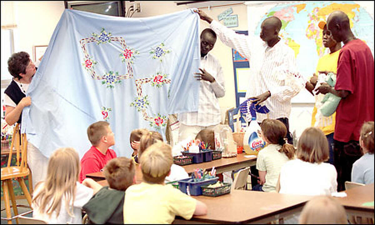In Liz Gjersee's second-grade class at Highland Elementary School in Lake Stevens, Chol, Daniel, Jacob Marial and David show the students linens from their homeland with the help of their guardian, Lynn Harding.