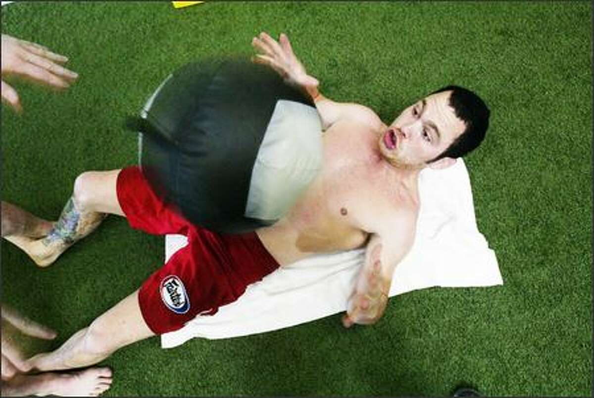 Leben is pounded in the stomach with a forty-pound ball as he trains.