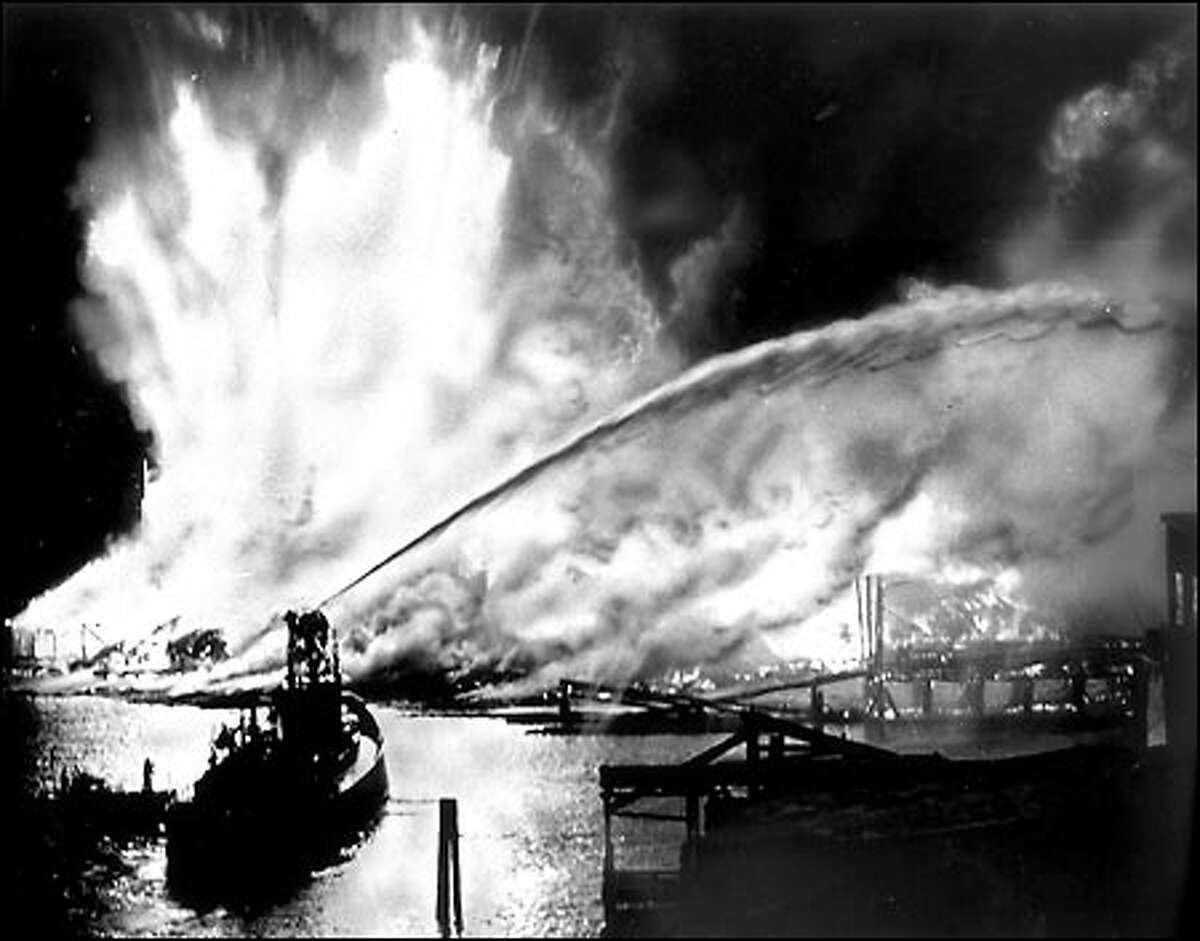 Seattle Cedar mill fire, 1958: On May 20, 1958, a massive fire destroyed the Seattle Cedar Lumber Manufacturing Co. at Salmon Bay in Ballard. The blaze, the largest in Seattle since the fire of 1889, started when sawdust ignited next to steam pipes. Fireboats poured water on the flames, which leaped hundreds of feet into the air in the kiln and storage area. Heat from the fire was felt more than two blocks away. The company, founded in the 1890s, was rebuilt and regained peak production a year later. P-I photographer Phil H. Webber shot this picture from the Ballard Bridge.