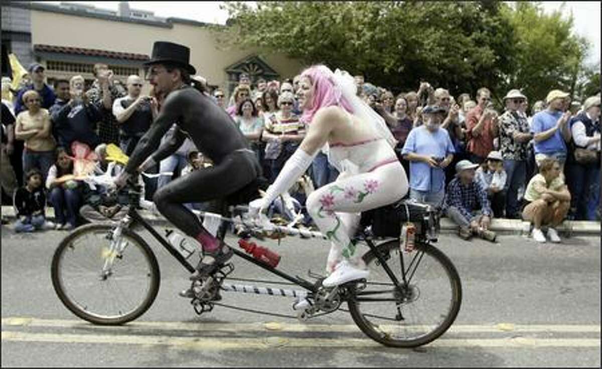 Painted up as newlyweds, a couple rides tandem in the 18th annual Summer Solstice Parade in Fremont. One of the parade's highlights is the procession of cyclists sporting nothing but body paint.