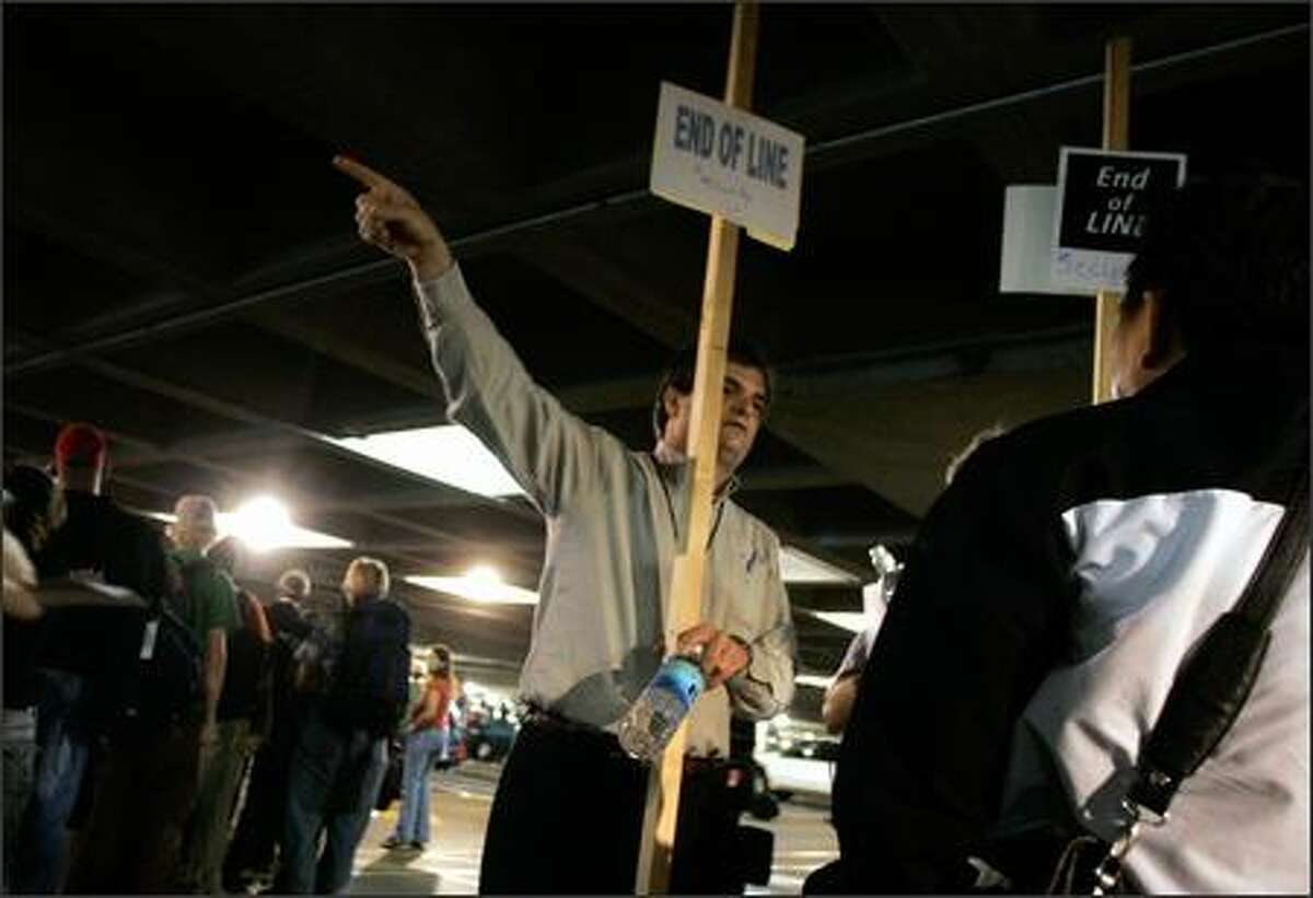 Port of Seattle employee Joe Krutenat directs air travelers at the end of the security screening line, which stretched into the short-term parking garage at Sea-Tac Airport Thursday morning.