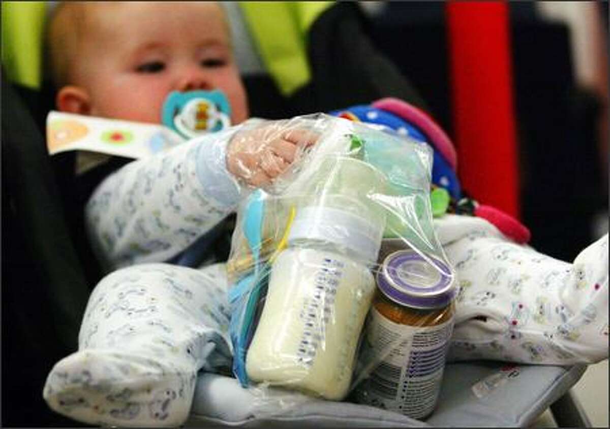 A baby holds onto a plastic bag filled with baby formula and food at Edinburgh airport, in Scotland, Thursday. Officials raised security to its highest level -- suggesting a terrorist attack might be imminent -- and banned hand-carried luggage on all trans-Atlantic flights. Huge crowds formed at security barriers as officials searching for explosives barred nearly every form of liquid outside of baby formula. (AP Photo/David Cheskin,PA)