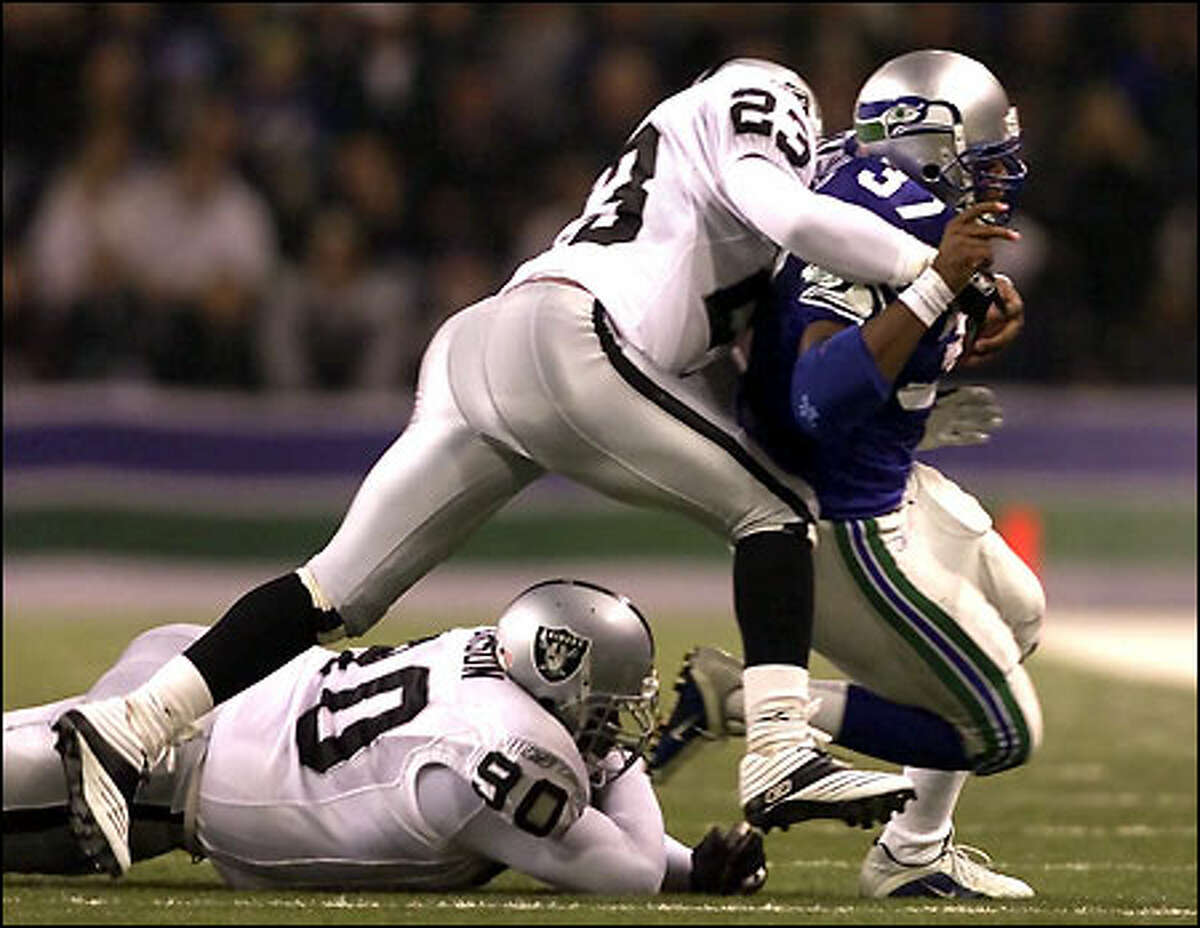 Seahawks' Shaun Alexander makes a gain of four yards with Raiders' Marquez Pope on his back with 10.30 minutes left in the second quarter at Husky Stadium.