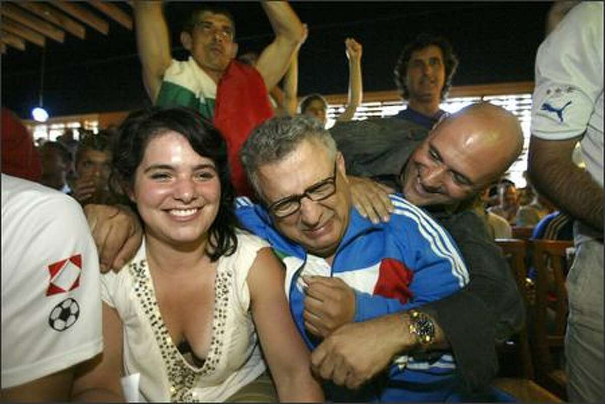 Mario Vellotti, center, hugs Anna Derr, left, as another Italian fan teases him inside the La Vita e Bella restaurant after they watched Italy beat France 5-3 in a penalty shootout for the World Cup.