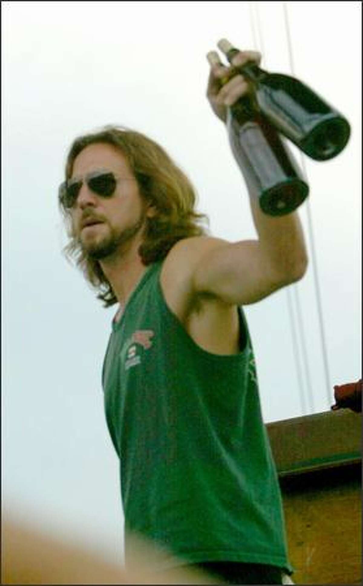 Eddie Vedder comes on stage with a little liquid to combat the heat during his performance.