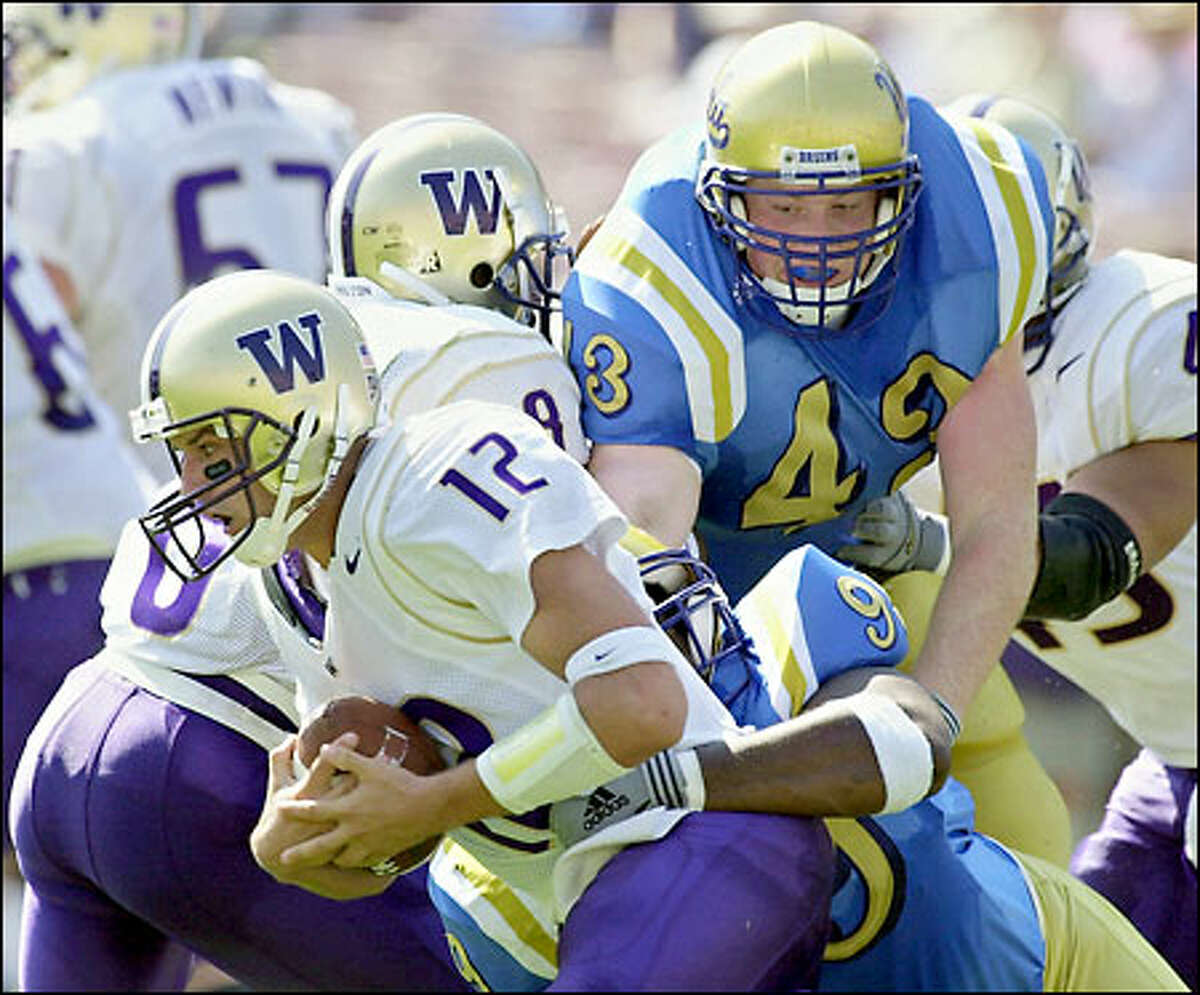 Washington quarterback Taylor Barton is sacked by UCLA's Kenyon Coleman (99) and Dave Ball (43) in the second quarter.
