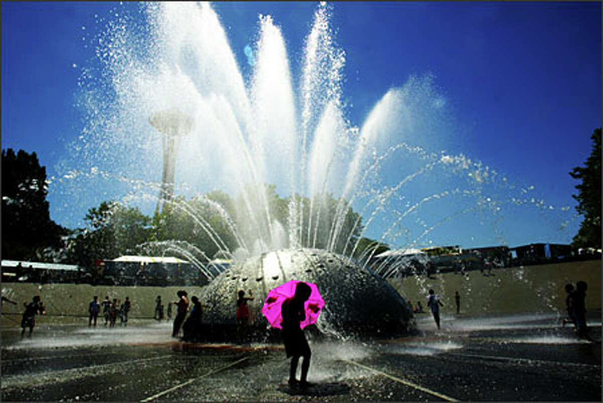 Isaiah Corpuz, 6, of Seattle says it's more fun playing in the Seattle Center International Fountain with an umbrella. Record-high temperatures scorched the Puget Sound region on July 21.