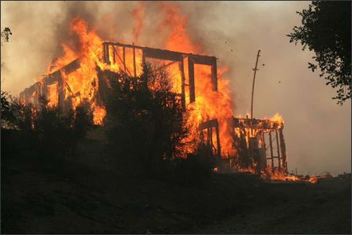 A wildfire burns a home located along Twin Pines Road near Cabazon,Calif., Thursday. (AP Photo/The Press Enterprise, William Wilson Lewis III)