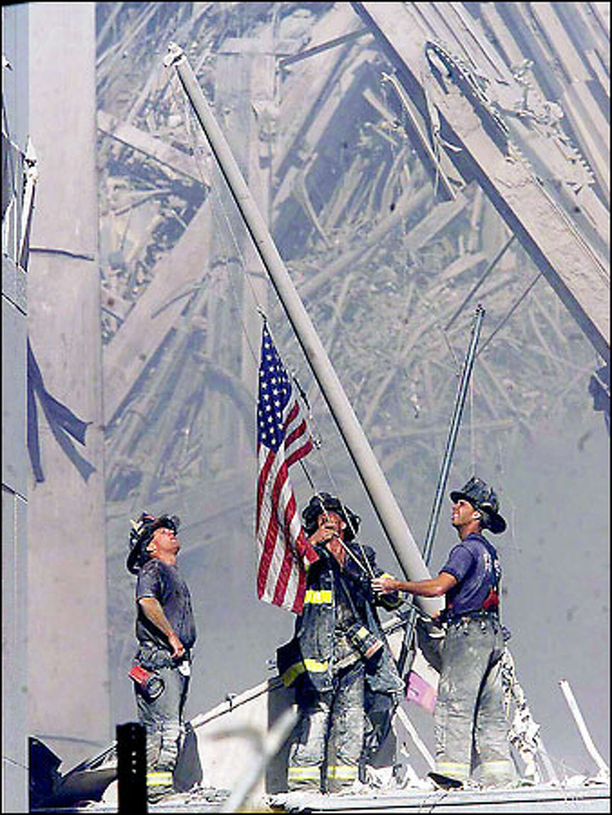 September 11: Brooklyn firefighters George Johnson, left, of Ladder 157, Dan McWilliams, center, of Ladder 157, and Billy Eisengrein, of Rescue 2, raise a flag at the World Trade Center in New York.