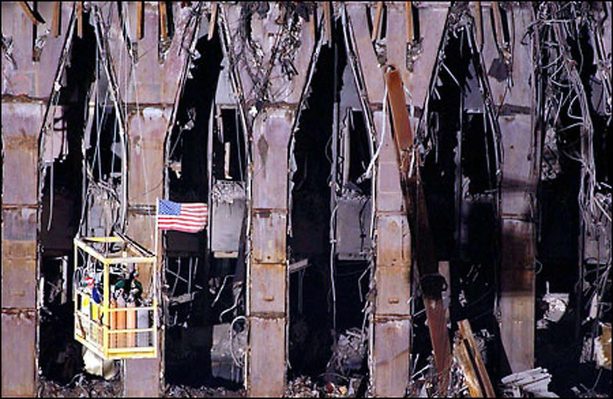 September 11: Workers are suspended from a crane in front of the remains of the North Tower.