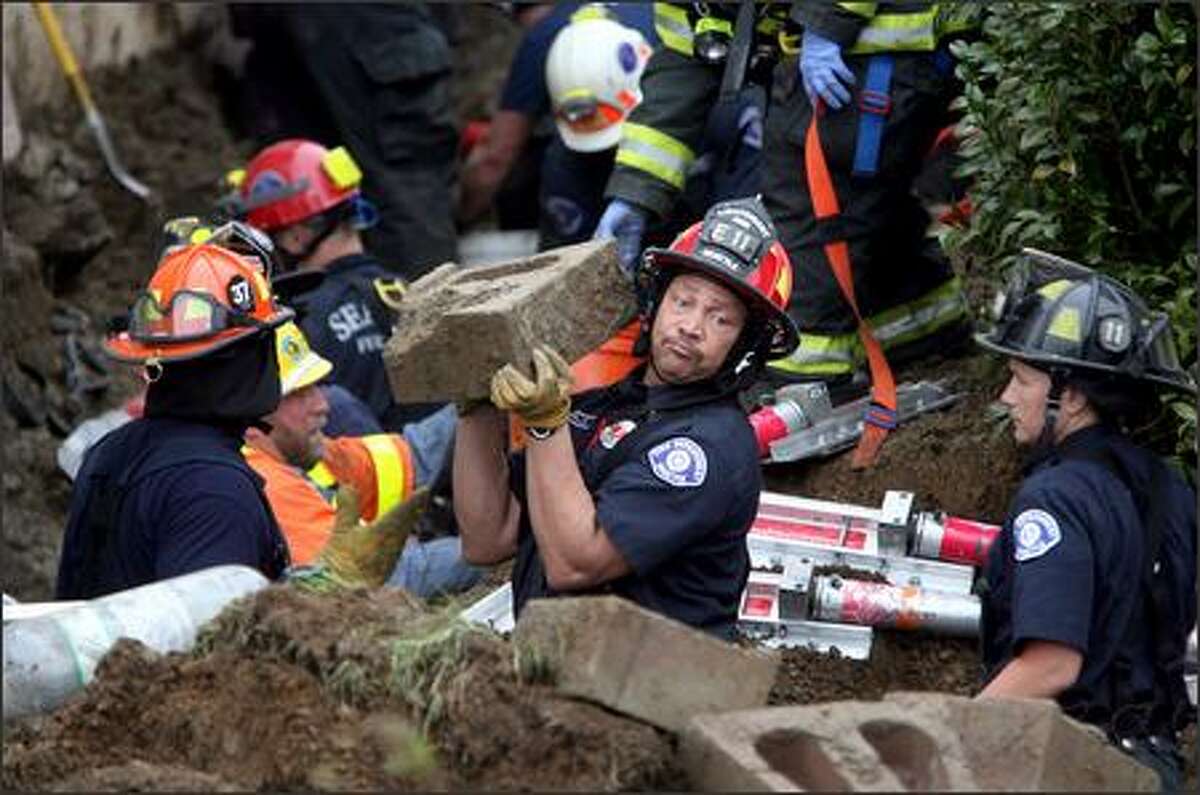 Seattle Fire Department Lt. Jerry Willis, with Engine 11, and other rescue workers form a bucket brigade in their battle to save a man buried Friday in a trench collapse in White Center.