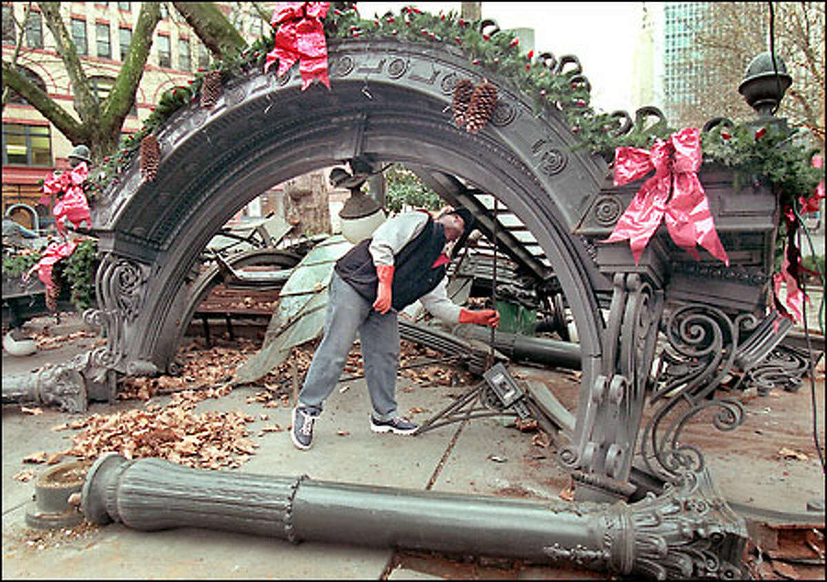 Larry Henderson of Seattle's Department of Parks and Recreation picks up pieces of the historic Pioneer Square pergola, which was destroyed by a truck.