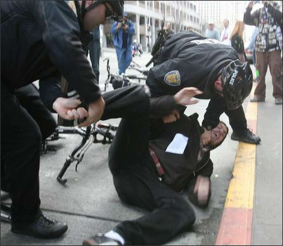 Seattle Police officers wrestle an anti-war protester to the ground. The momentary scuffle ended with the arrest of a 22-year-old Tacoma activist. The man was arrested for allegedly assaulting two counter-protesters, Seattle Police spokesman Sean Whitcomb said. No one was hurt. The man was participating in an anti-war protest to mark the fourth anniversary of the Iraq war. The protest starting at Westlake Center and progressed through the downtown area on Sunday in Seattle