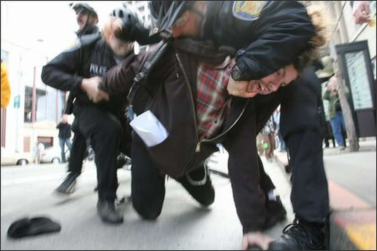Seattle Police officers wrestle an anti-war protester to the ground. The momentary scuffle ended with the arrest of a 22-year-old Tacoma activist. The man was arrested for allegedly assaulting two counter-protesters, Seattle Police spokesman Sean Whitcomb said. No one was hurt. The man was participating in an anti-war protest to mark the fourth anniversary of the Iraq war. The protest starting at Westlake Center and progressed through the downtown area on Sunday in Seattle.