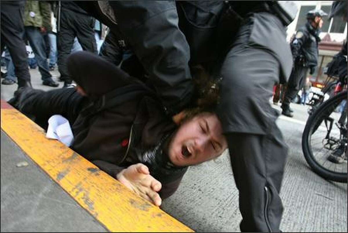 Seattle Police officers wrestle an anti-war protester to the ground. The momentary scuffle ended with the arrest of a 22-year-old Tacoma activist. The man was arrested for allegedly assaulting two counter-protesters, Seattle Police spokesman Sean Whitcomb said. No one was hurt. The man was participating in an anti-war protest to mark the fourth anniversary of the Iraq war. The protest starting at Westlake Center and progressed through the downtown area on Sunday in Seattle