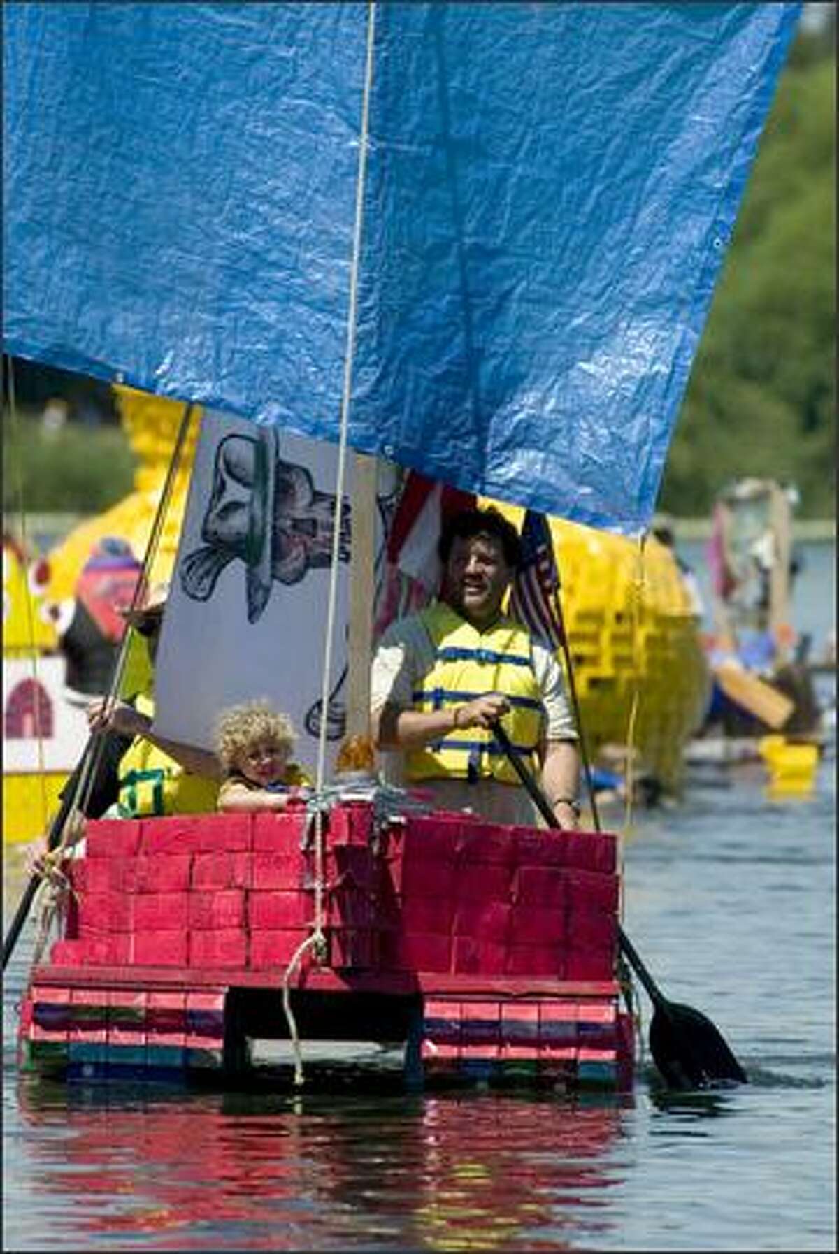 Boaters row towards the finish line in the Seafair Baffle Gab Milk Carton Derby along the southwest shore of Green Lake in Seattle.