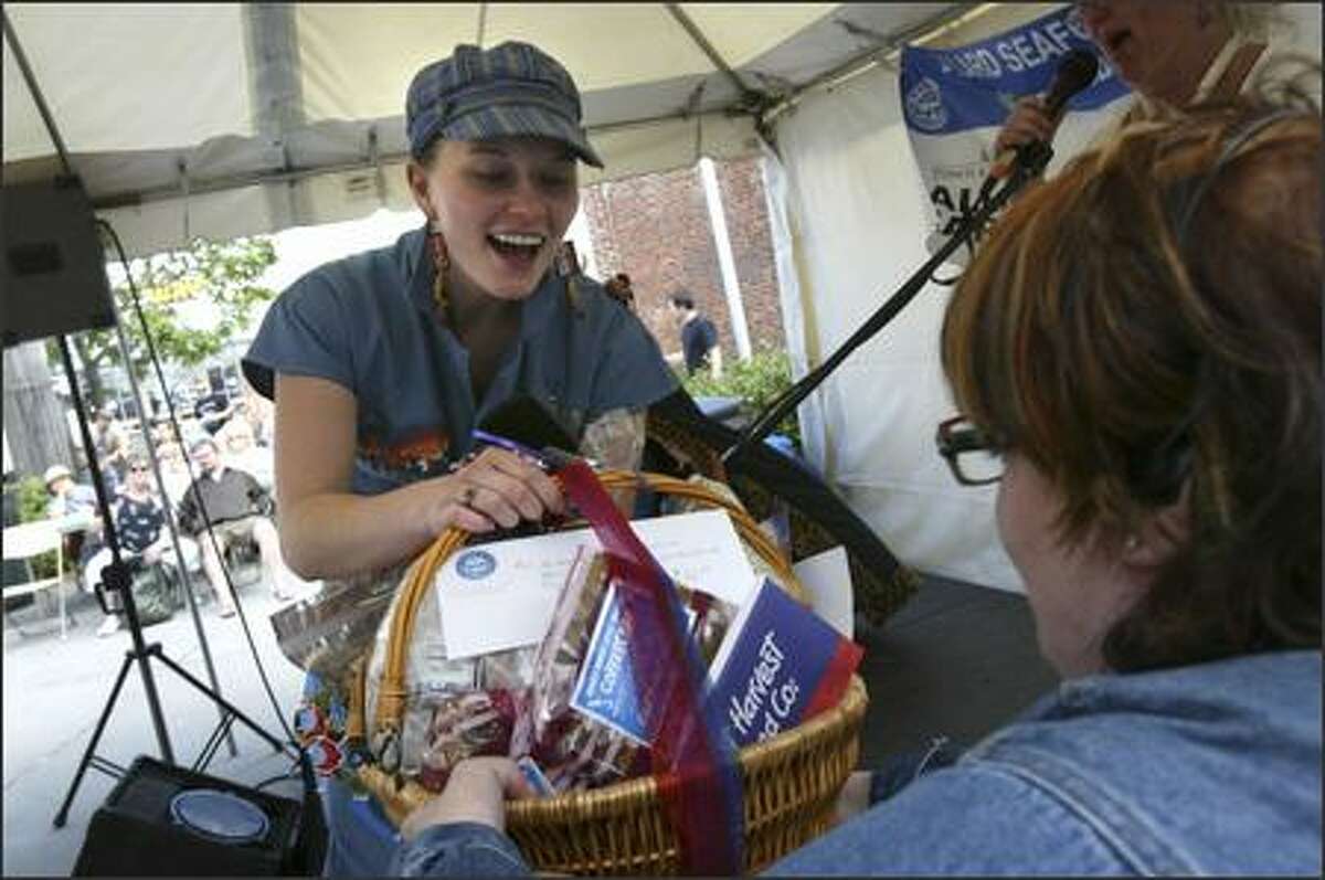 Ciara Griffin of Ballard receives a prize basket from Beth Williamson Miller for her second-place finish in the coverall competition at the 33nd Annual Ballard SeafoodFest.