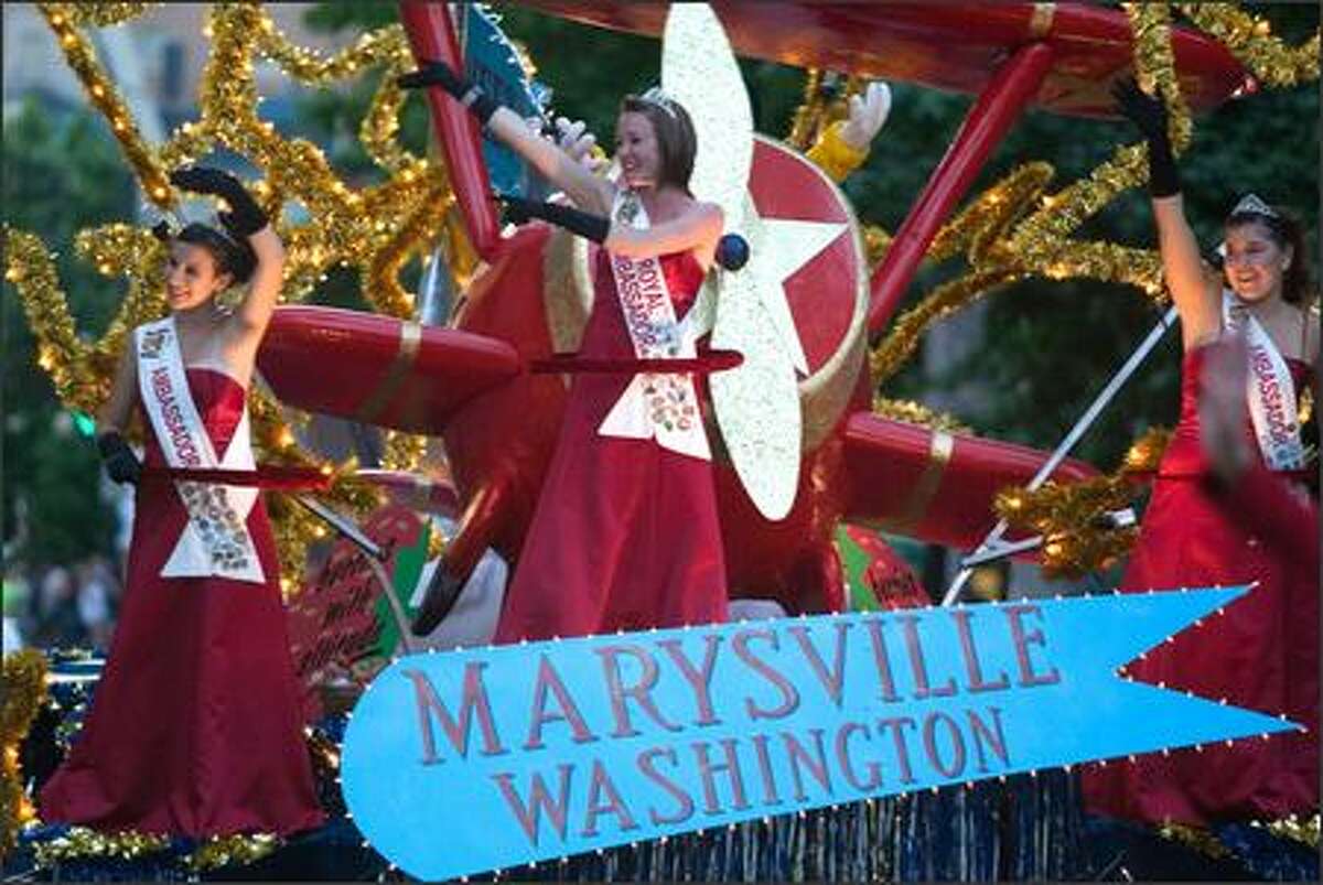 Marysville's float, filled with crimson-clad ambassadors, waves to the crowd during the 58th annual Seafair Torchlight Parade through downtown Seattle.