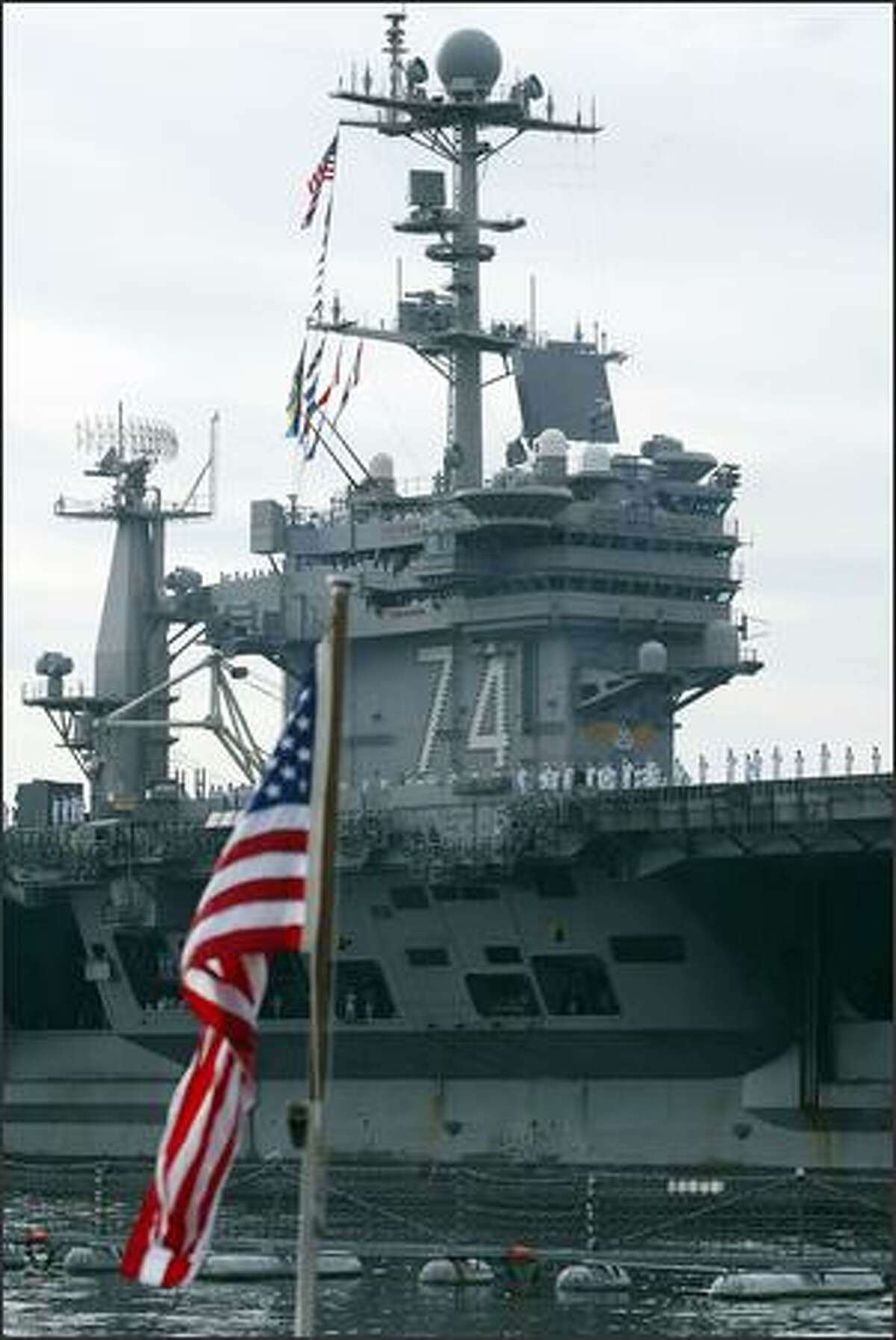 The superstructure of the USS Stennis passes before the flag on the submarine USS Seawolf at the Naval Base Kitsap in Bremerton, Wash., Friday August 31, 2007. The Stennis returned to its home port after a half-year deployment in the waters of the Middle East in support of the fighting in Afghanistan and Iraq.