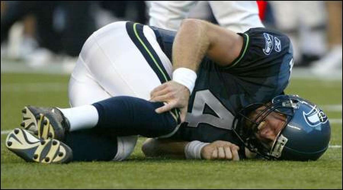 Seahawks QB Trent Dilfer grabs his right knee after being hit by Indianapolis' Bratzke in the first half. Early reports said he had a sprained knee.