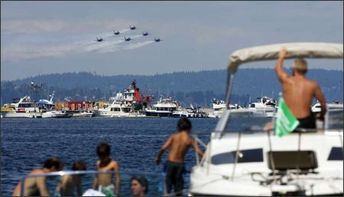 The Blue Angels fly along the boats parked at the log boom for hydro racing on Lake Washington.