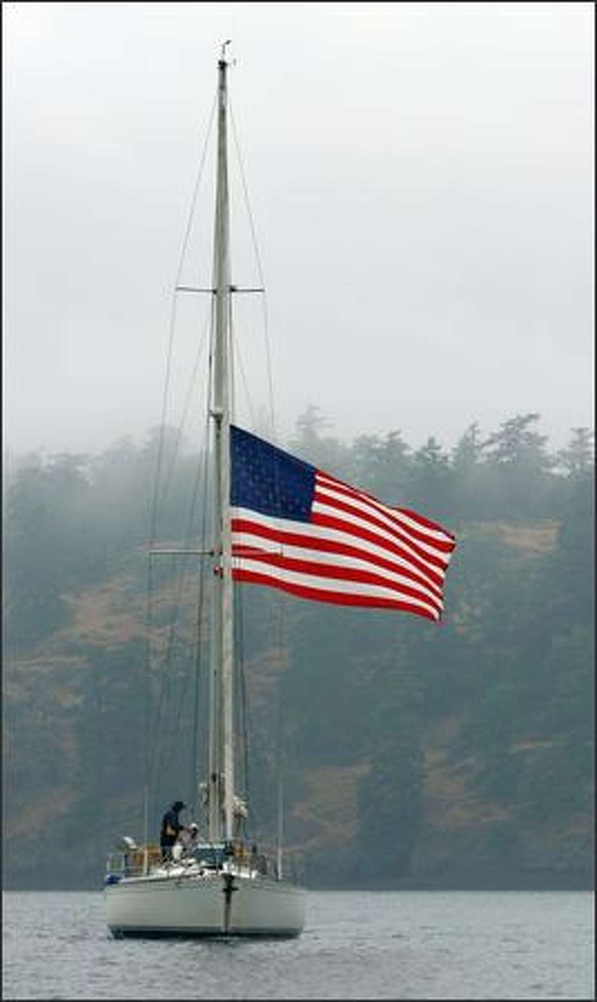 A sailboat flying the Stars and Stripes passes Spieden Island in the San Juan Islands.