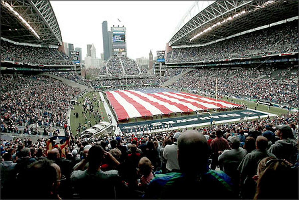 The U.S. flag covers the floor of the Seahawks Stadium during the National Anthem.
