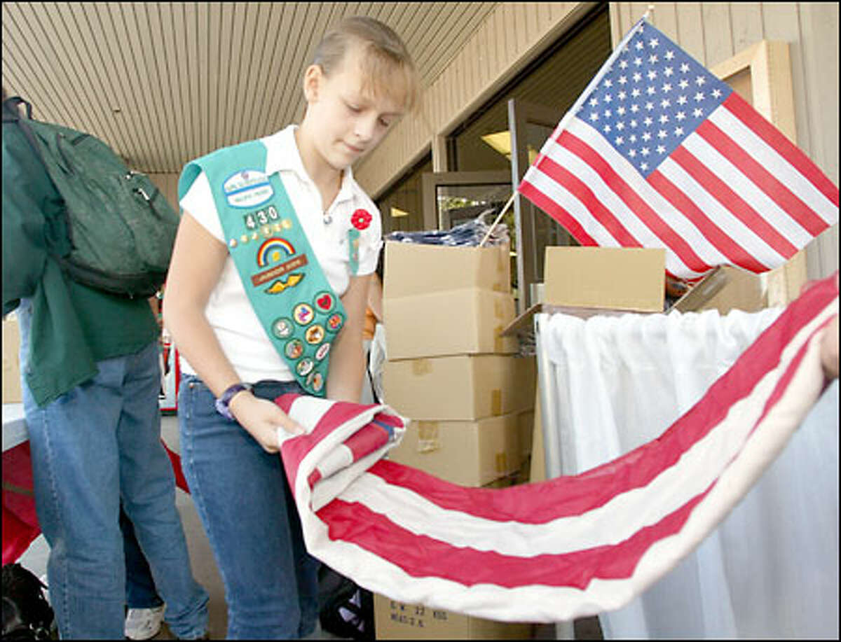 Girl Scout Maggie Roger, 11, folds a used flag that a visitor exchanged for a new one at the Puyallup Fair. About 500 old flags were turned in for new ones.