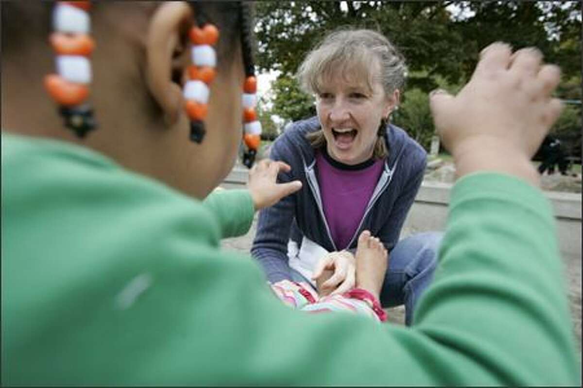 Sara Cole tickles the feet of adopted daughter Rosie Barnes-Cole, 4, while putting her shoes on at Meridian Park.