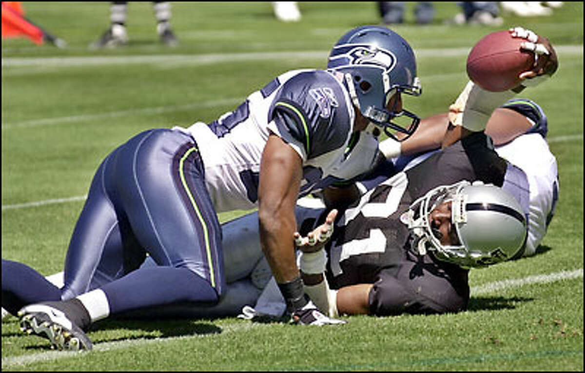 Raiders wide receiver Tim Brown flashes the ball after catching an 8-yard touchdown in front of Seahawks strong safety Reggie Tongue during the first quarter.