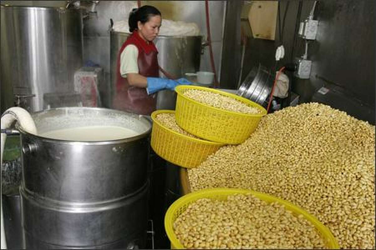 Washed soybeans wait to be grinded into a slurry, left, and then boiled at the Chuminh Tofu Factory.