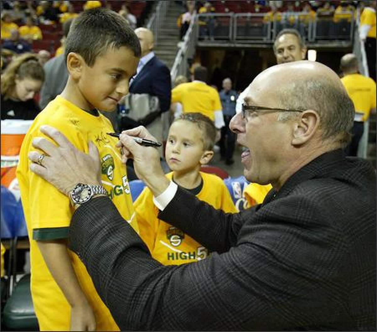 Sonics radio announcer Kevin Calabro autographs 8-year-old Robby Proano's shirt under the watchful eye of brother Michael, 6, prior to the home opener against the Phoenix Suns.