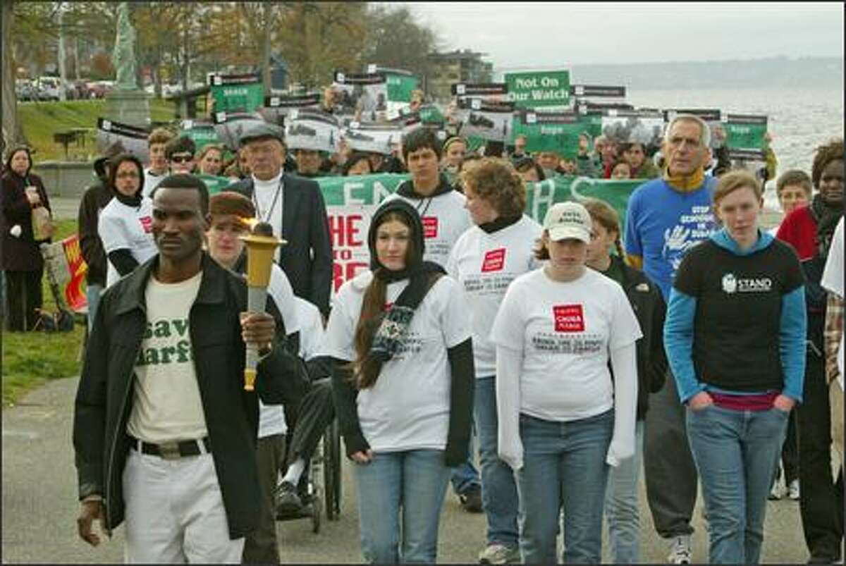 Darfur genocide survivor Ibrahim Adam, front at left, carries the symbolic Dream for Darfur Olympic Torch in the last leg of the relay along Alki Beach.