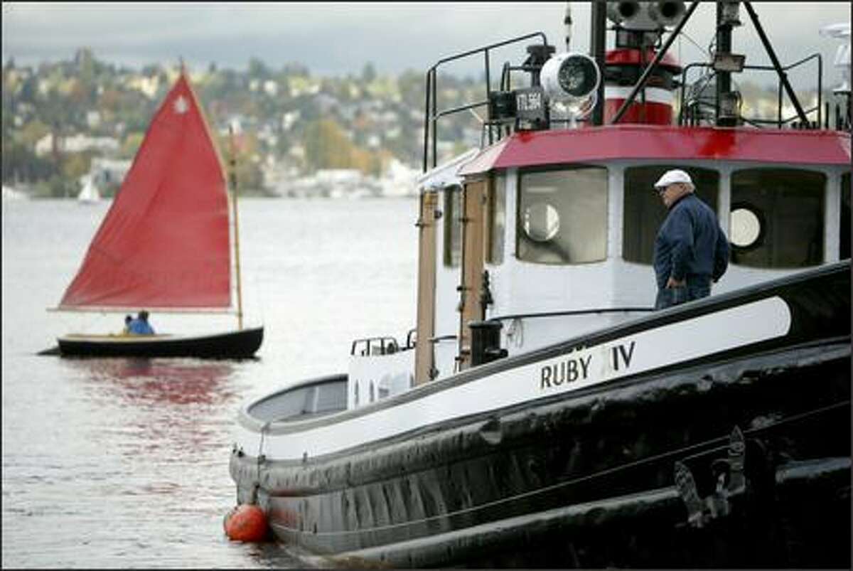 A sailboat passes behind the Ruby XIV, a 65-foot tugboat built in 1945, during the Classic Workboat Show, sponsored by Northwest Seaport and The Center for Wooden Boats, at Lake Union Park in Seattle. The event featured several workboats, mostly tugs from the '20s, '30s and '40s.