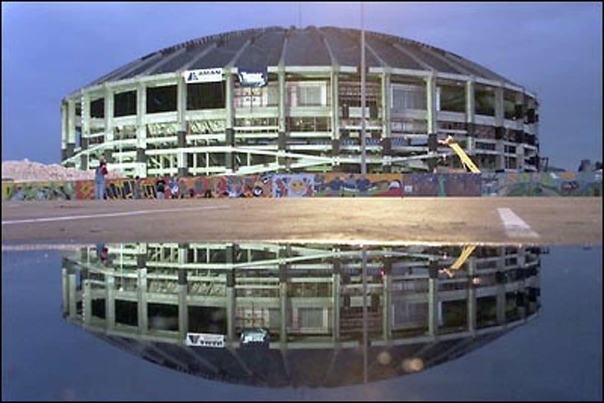 Last look: The Dome is reflected in a puddle as dawn breaks on Sunday, March 26, a few hours before the stadium's destruction.