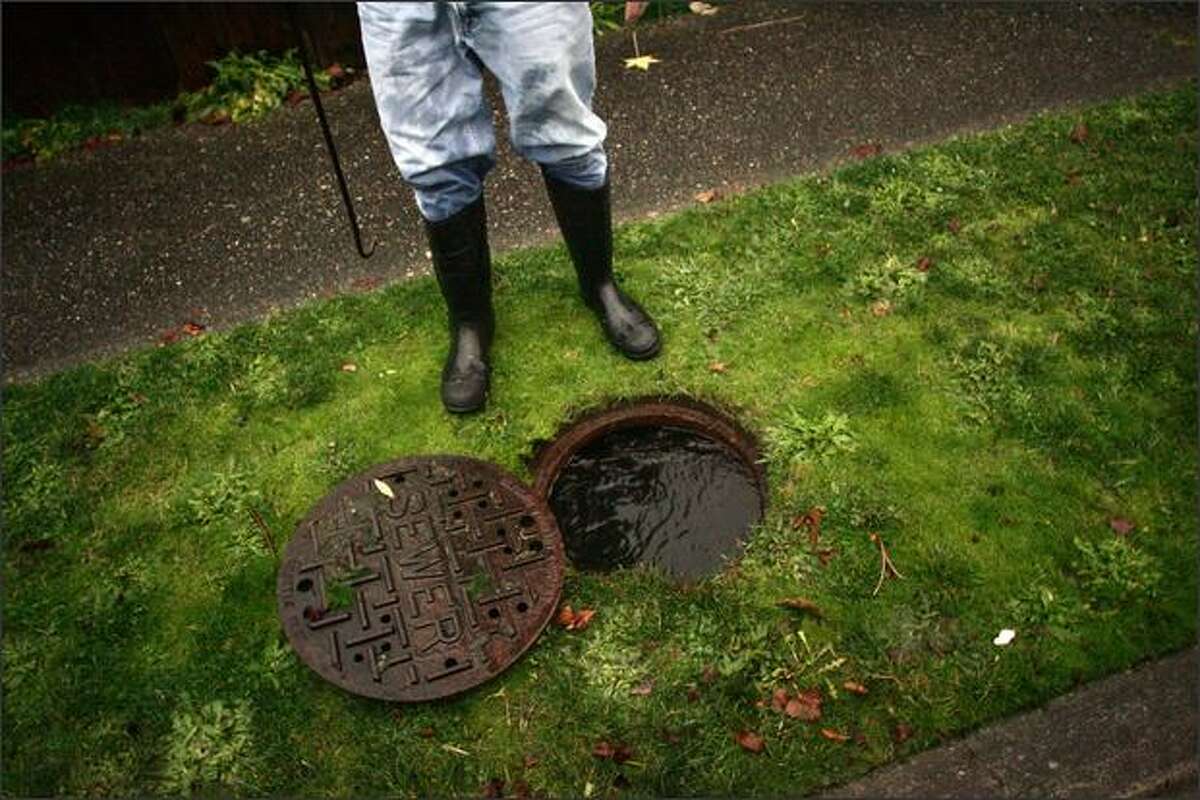 Dave Barton stands over a sewer line that he opened after heavy rains caused major flooding at his home in Greenwood in Seattle.