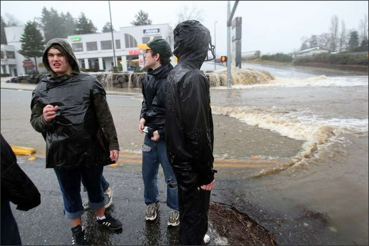 Woodinville High School seniors PJ Petterson, (left) Steven Brey, and Greg Kachmarik try to figure out how they will get home at the intersection of Little Brear Creek Parkway/ NE 177th PL and 131st Ave NE which had severe flooding in Woodinvellie, Wash. on December 3, 2007. The area was devastated by a winter storm. The kids decided to leave their cars at school and walk home because the traffic was so bad.