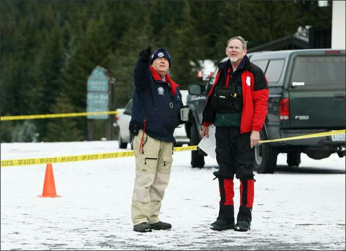 Art Farash, Seattle Mountain Rescue,(left) and Ralph Javins, Ski Patrol Rescue Team King County, look up the mountain from the base camp as the search goes on for three missing snowboarders on Crystal Mountain.
