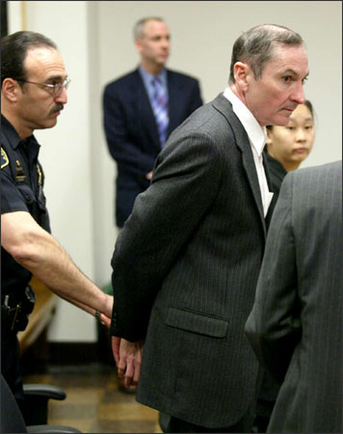 William Joice is handcuffed before being taken out of King County Superior Court after he was found guilty Tuesday of first-degree attempted murder in the shooting of Bellevue lawyer Kevin Jung.