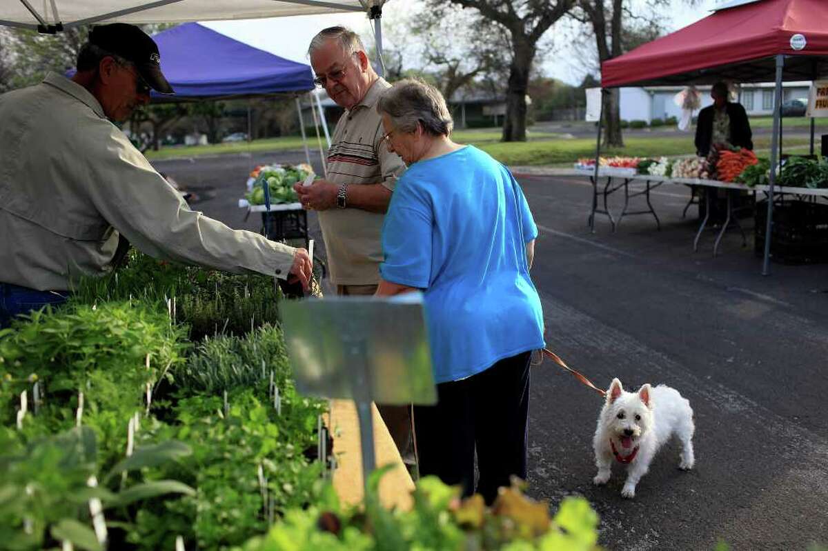 Michael and Gabriele McNiff, with their dog, Jenny, shop for herbs from Juan Gonzalez (left) at the Auntie Pen’s Backyard Herbs booth at the Farmer’s Market in Leon Valley.